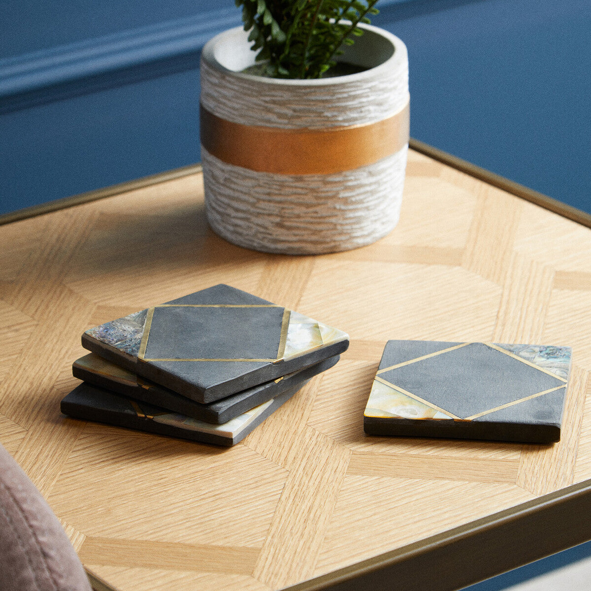 Set of geometric coasters on a wooden table with a plant in the background