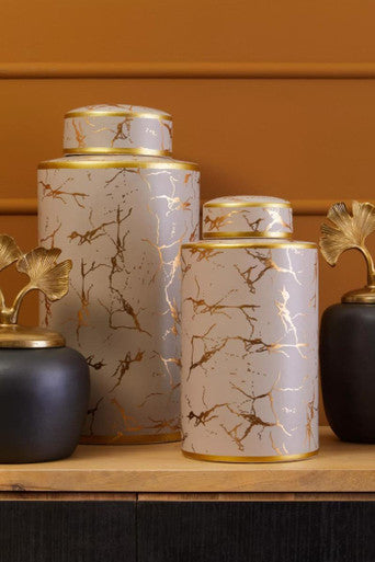 Decorative jars with marble-like patterns and gold accents on a wooden surface.