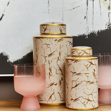 Decorative jars with marble pattern and pink glass on a wooden surface