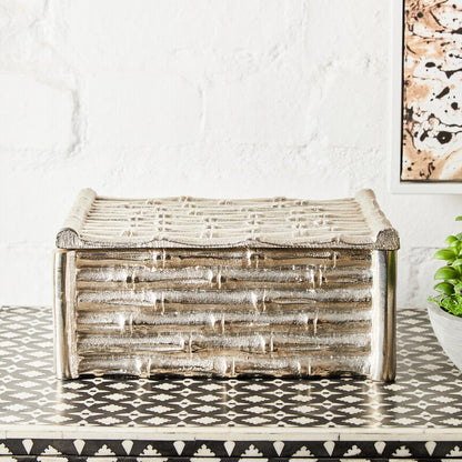 Wooden storage box on a patterned floor with a white wall and abstract art in the background