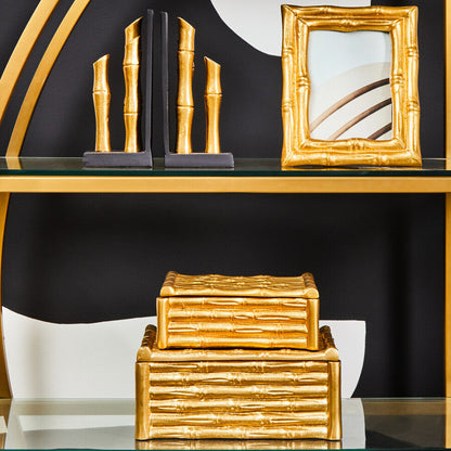 Decorative gold and black bookends and frames on a shelf against a black background