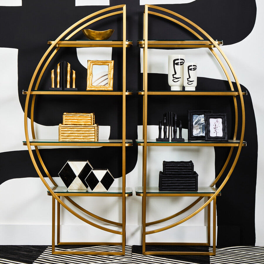 Gold circular shelving unit with decorative items against a black and white abstract background