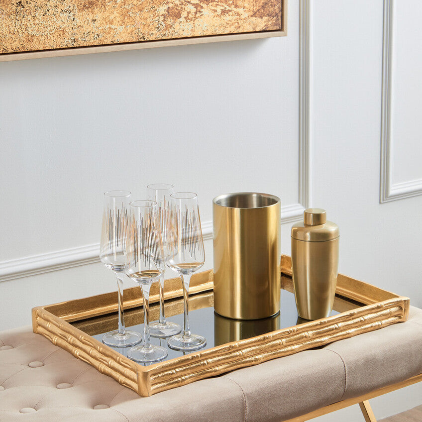 Decorative tray with gold accents on a table, featuring wine glasses and a decorative vase.