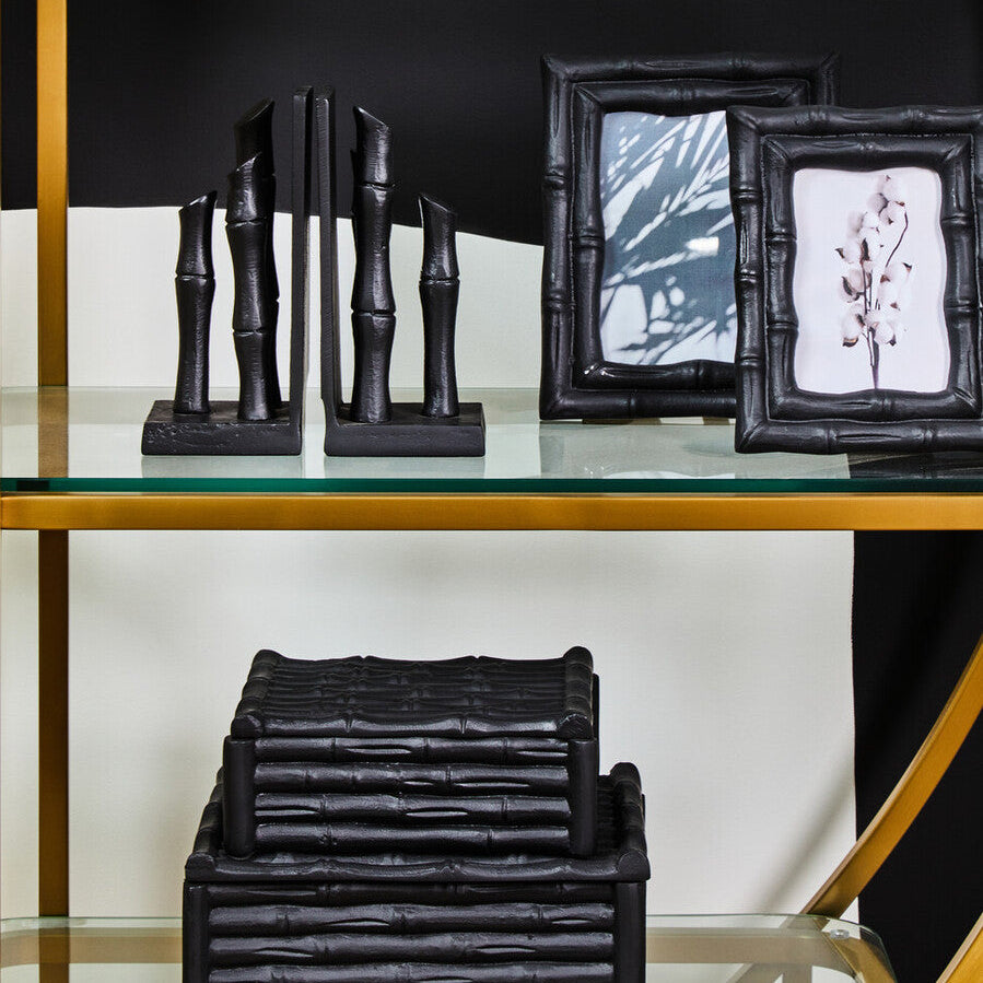 Decorative items including black bamboo sculptures and picture frames on a glass shelf.