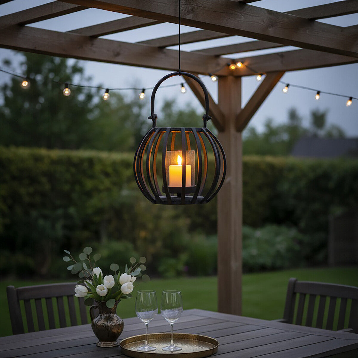 Outdoor setting with hanging lantern, table, chairs, and string lights.