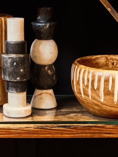 Decorative stone sculptures and a wooden bowl on a dark surface