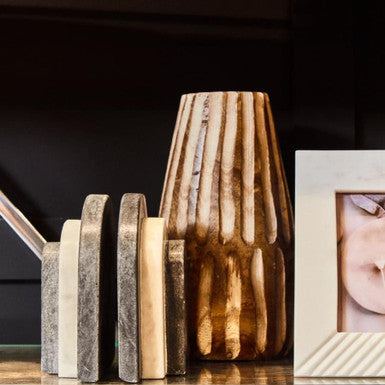 Decorative wooden vase on a shelf with a photo frame in the background