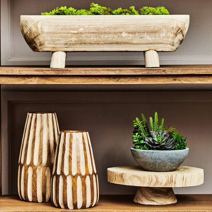 Decorative wooden planters and vases on a shelf against a neutral background
