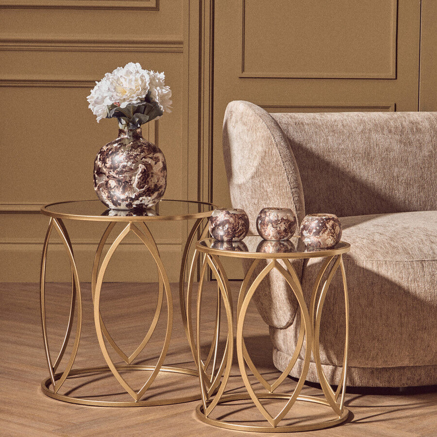 Gold side table with decorative items next to a beige armchair in a room with green walls.