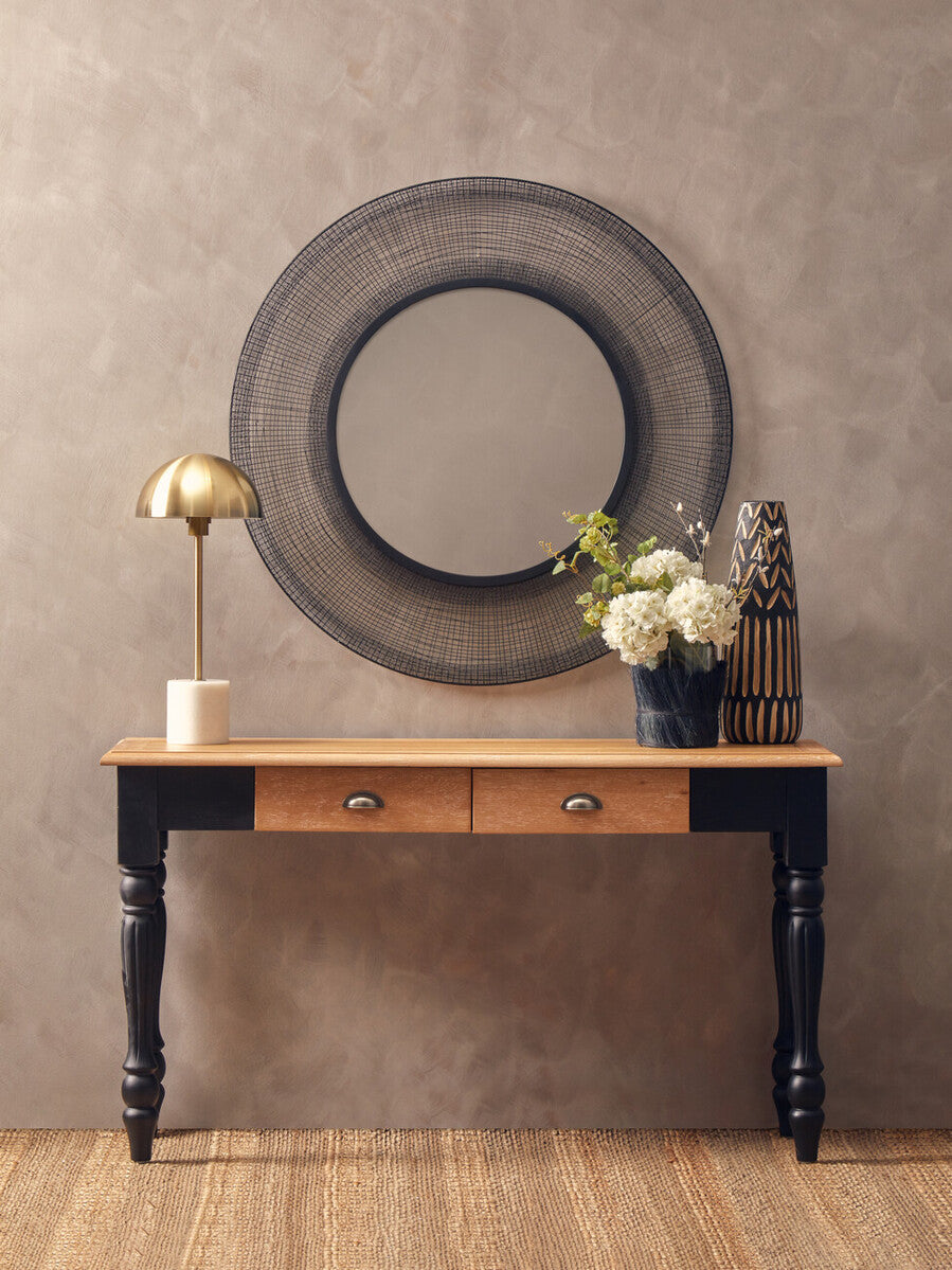 Wooden console table with black legs against a beige wall, featuring decorative items.