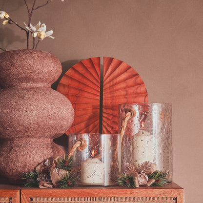 Decorative setting with candles, flowers, and a red decorative plate on a wooden surface.