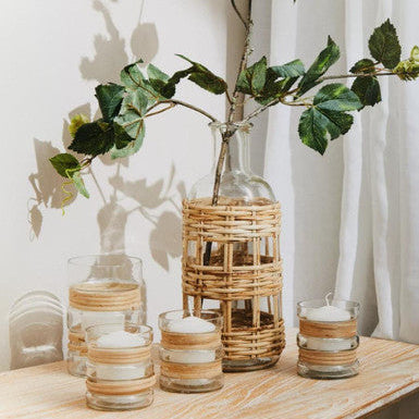Decorative setting with glass vases and candles on a wooden surface.