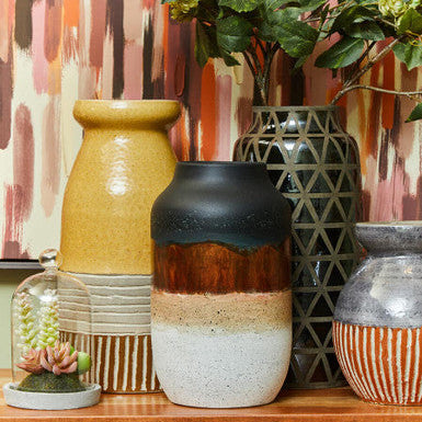 Collection of ceramic vases on a wooden surface with a colorful abstract background
