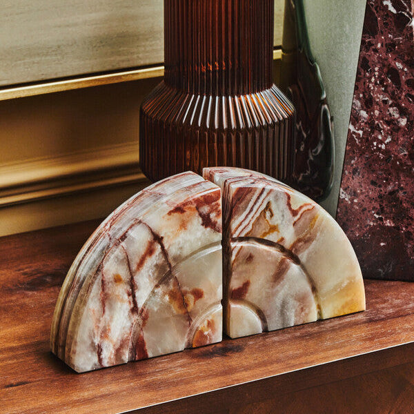 Marble coasters on a wooden surface with decorative lamp and vase in the background