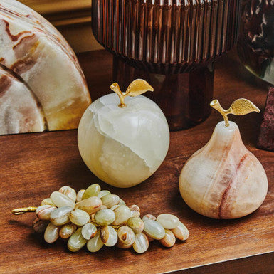 Decorative stone fruits and grapes on a wooden surface with a textured background