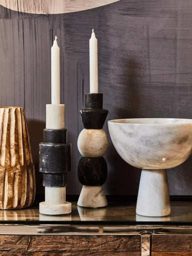 Decorative candle holders and a marble bowl on a wooden surface with a dark textured wall background.