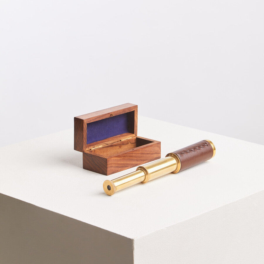 Small brass telescope with wooden case on a white surface