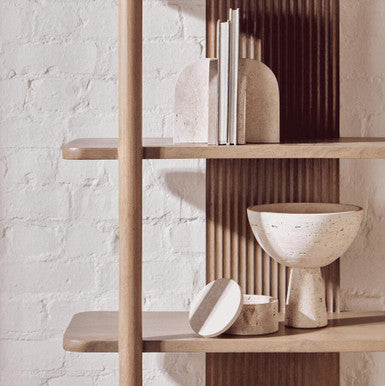 Wooden shelf with decorative items against a light brick wall