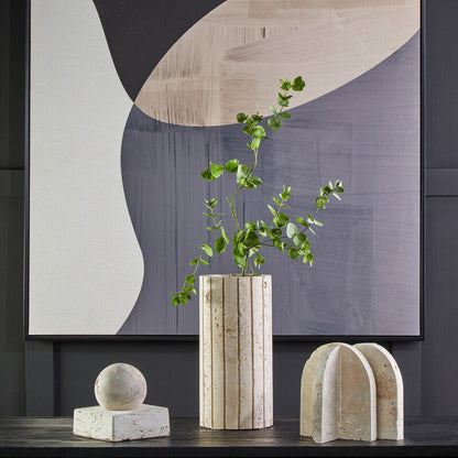Decorative setup with abstract wall art, vase, and sculptures on a dark surface.
