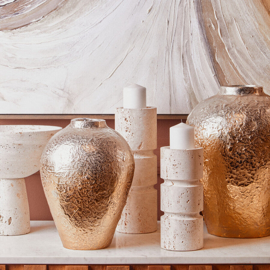 Decorative vases and candles on a shelf with a marble wall background