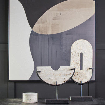 Abstract art piece on a dark wall with decorative items below.