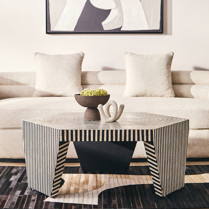Modern living room with a striped coffee table, beige sofa, and abstract art on the wall.