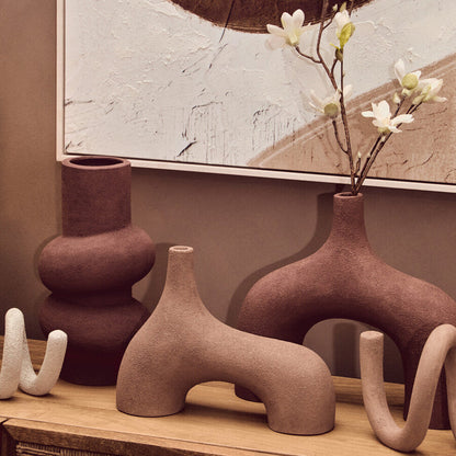 Decorative vases on a wooden surface with abstract art in the background