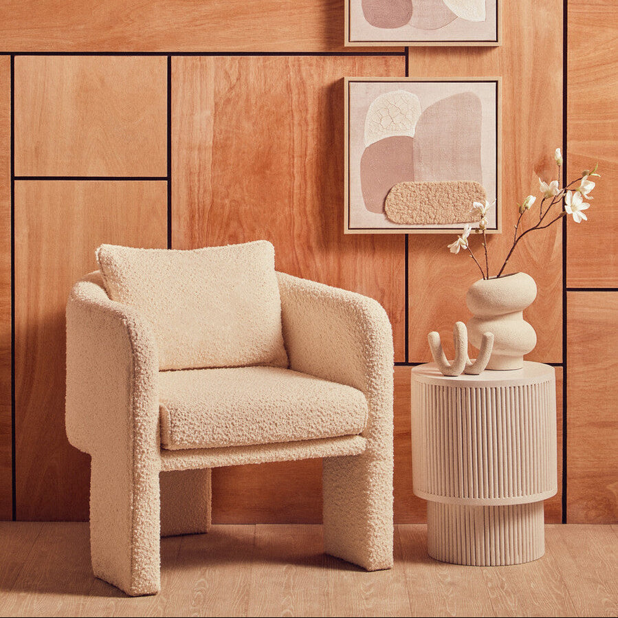 Beige textured armchair in a room with wooden walls and abstract art.