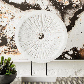 Decorative white lamp with textured design on a table against a marble-patterned wall.