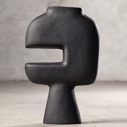 Black abstract vase on a light gray surface with a neutral background