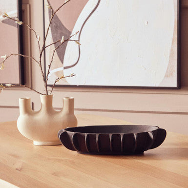 Decorative items on a wooden surface with abstract art in the background