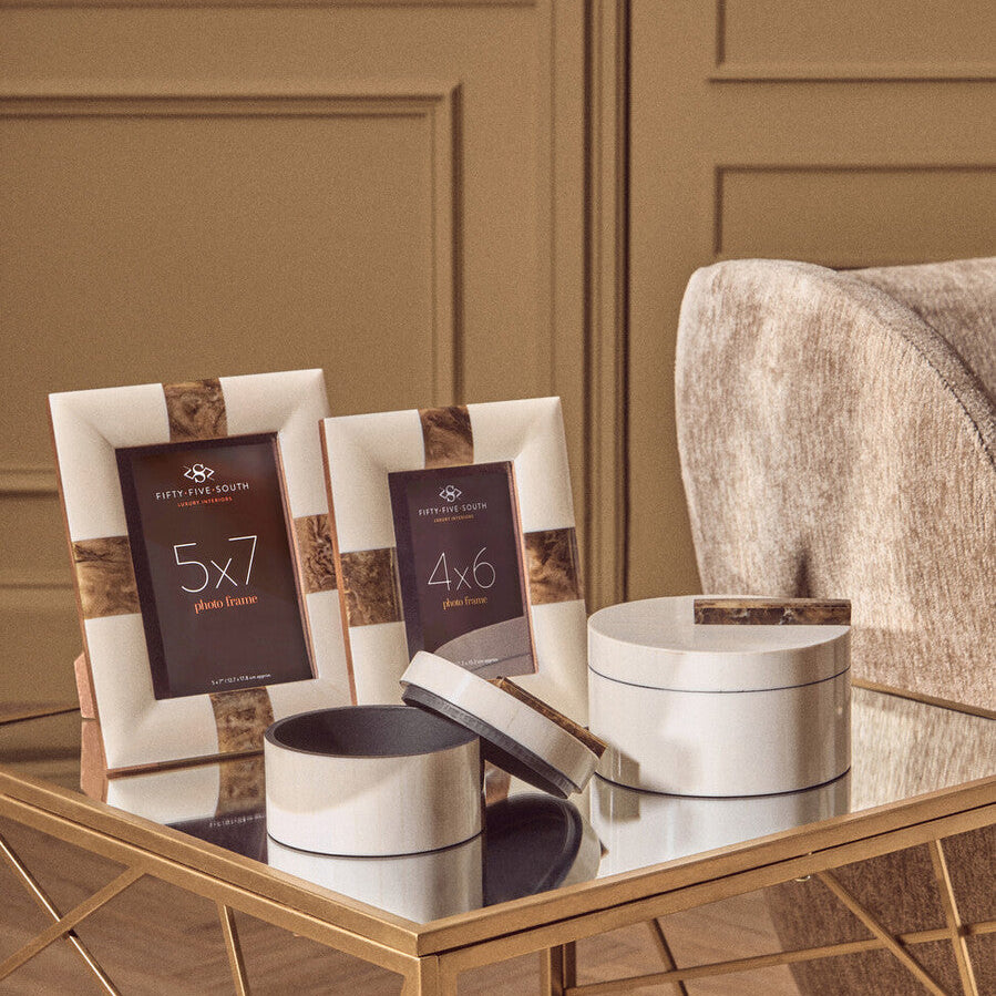 Decorative photo frames and boxes on a reflective surface with a neutral background