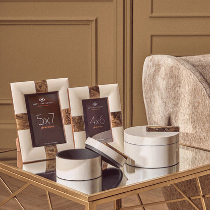 Decorative photo frames and boxes on a reflective surface with a neutral background