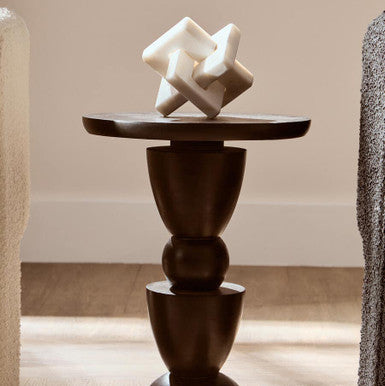 Decorative sculpture on a dark wooden pedestal against a neutral background