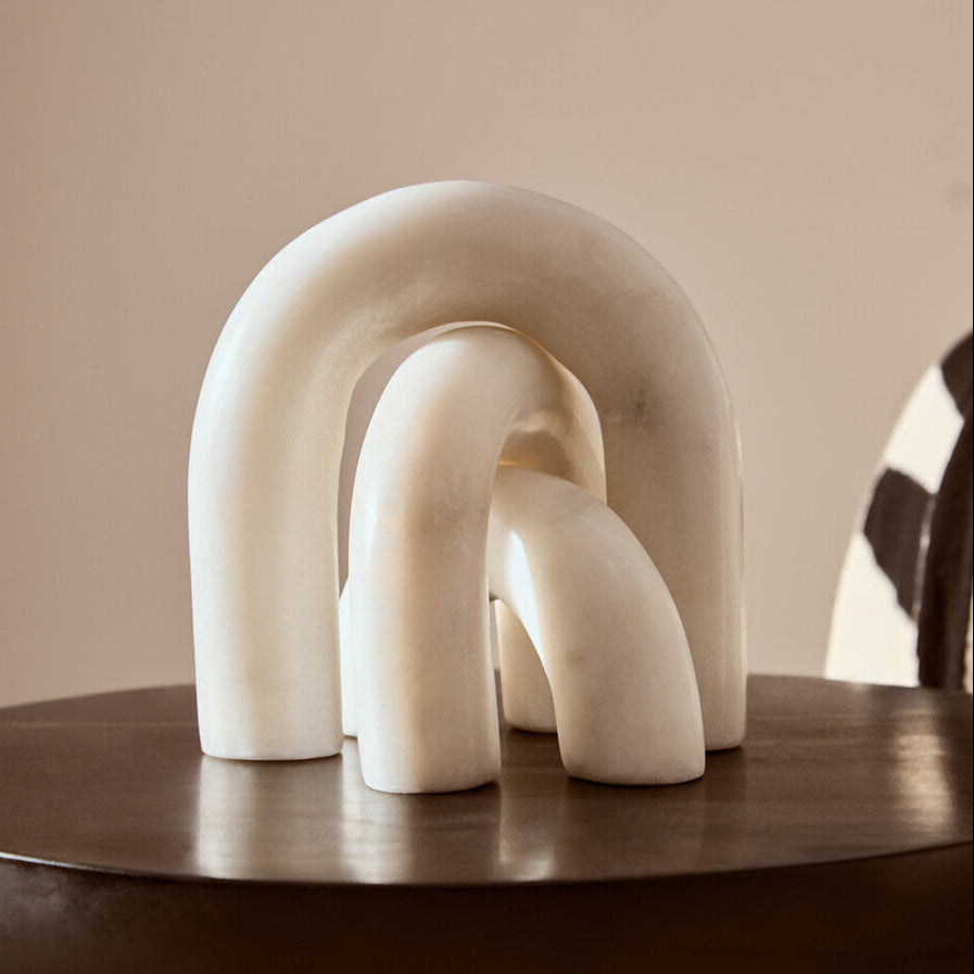 White marble sculpture on a wooden table with a neutral background
