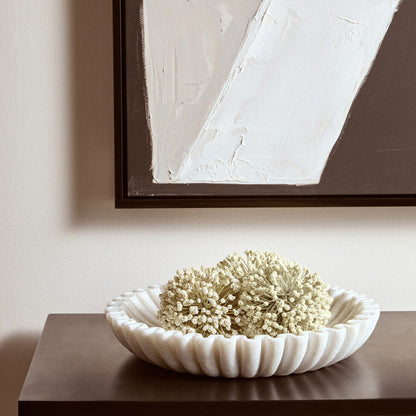Decorative bowl with white flowers on a wooden surface with abstract art in the background