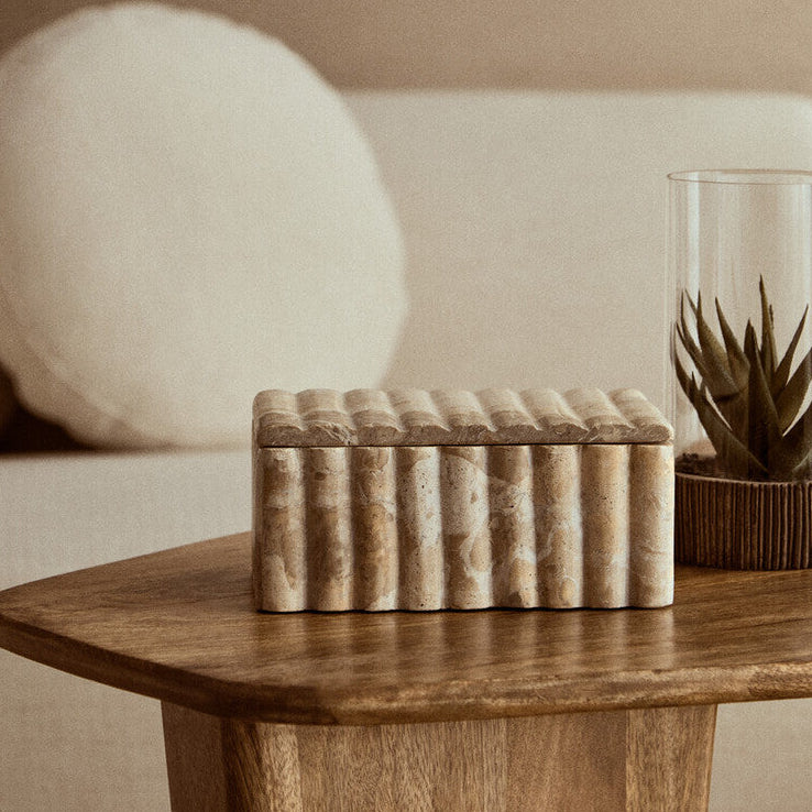 Wooden side table with decorative box and plant against a beige wall
