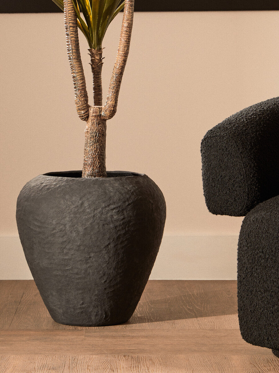 Decorative plant pot with a textured finish on a wooden floor.