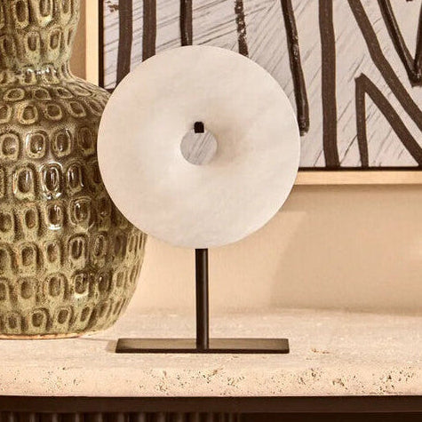 Decorative vase with branches on a table in front of abstract wall art