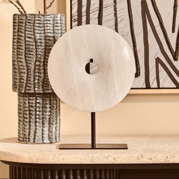 Decorative vase with floral branches on a table next to abstract wall art.
