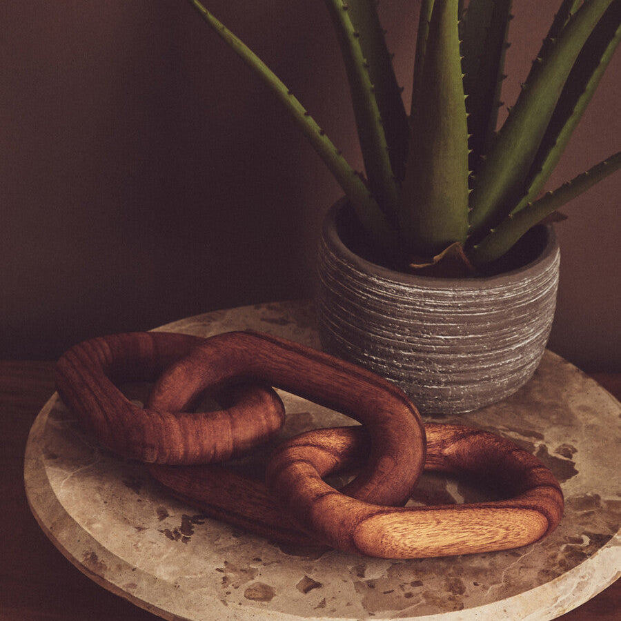 Decorative chain on a marble stand with a potted plant in the background