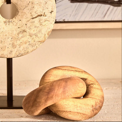 Decorative stone lamp and wooden knot sculpture on a surface with a blurred abstract painting in the background.