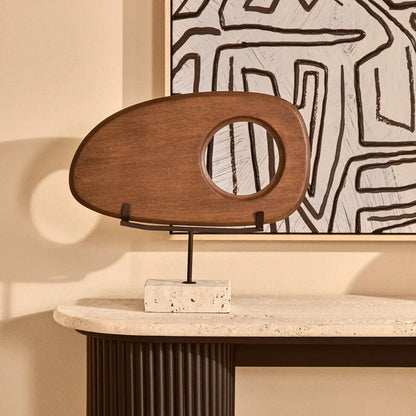 Wooden sculpture on a stand against a wall with abstract art