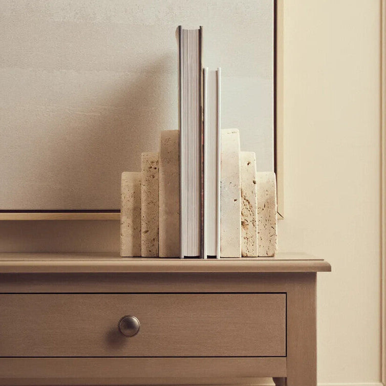 Wooden console table with a drawer and decorative items against a beige wall.