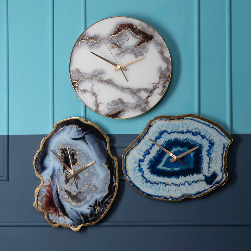 Three decorative wall clocks with agate-like designs on a blue door.