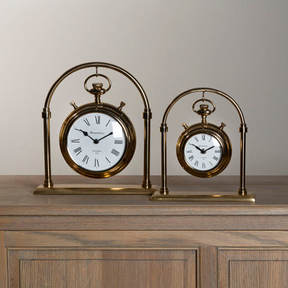 Two vintage-style table clocks on a wooden surface with a neutral background