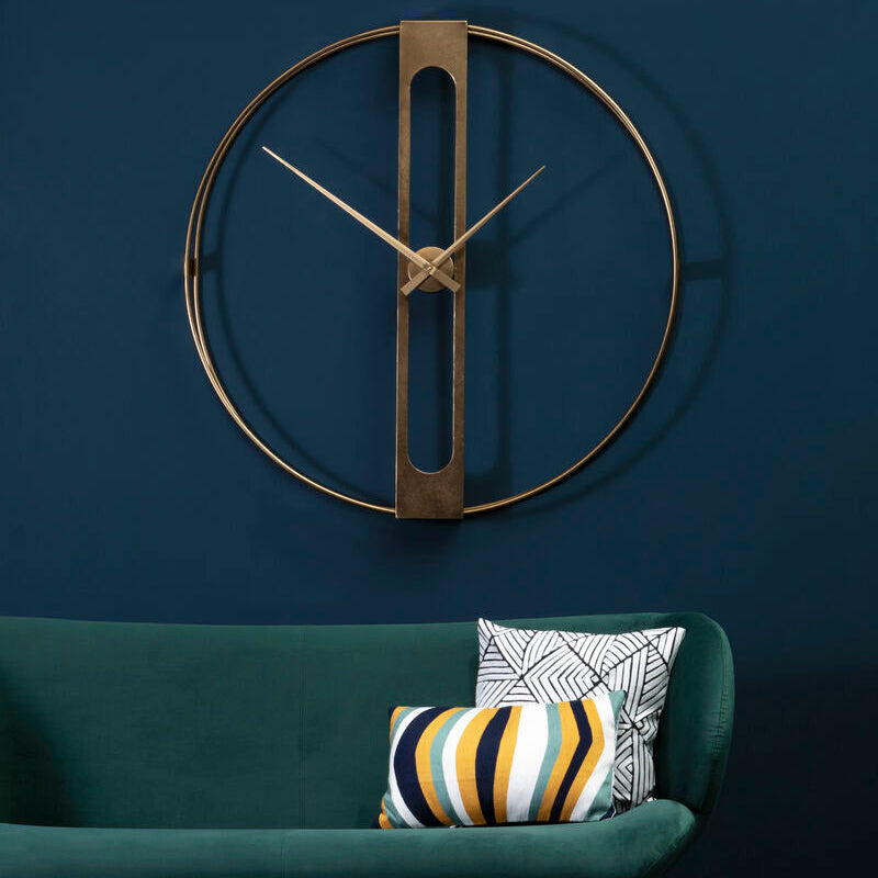 Modern wall clock on a blue wall above a green sofa with decorative pillows.
