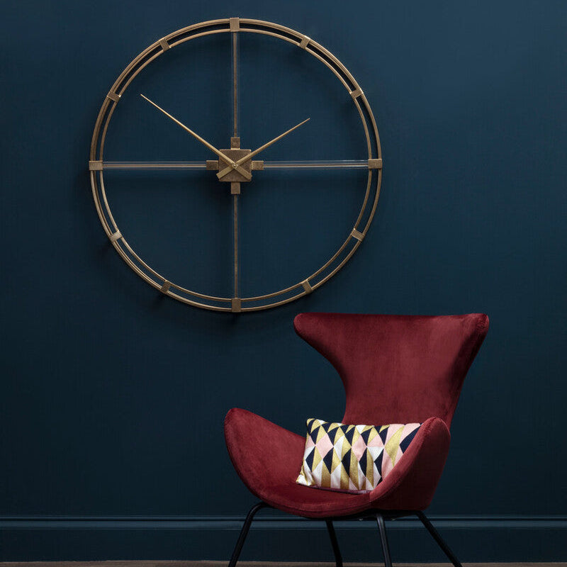 Red chair with a patterned pillow against a dark blue wall with a decorative clock.