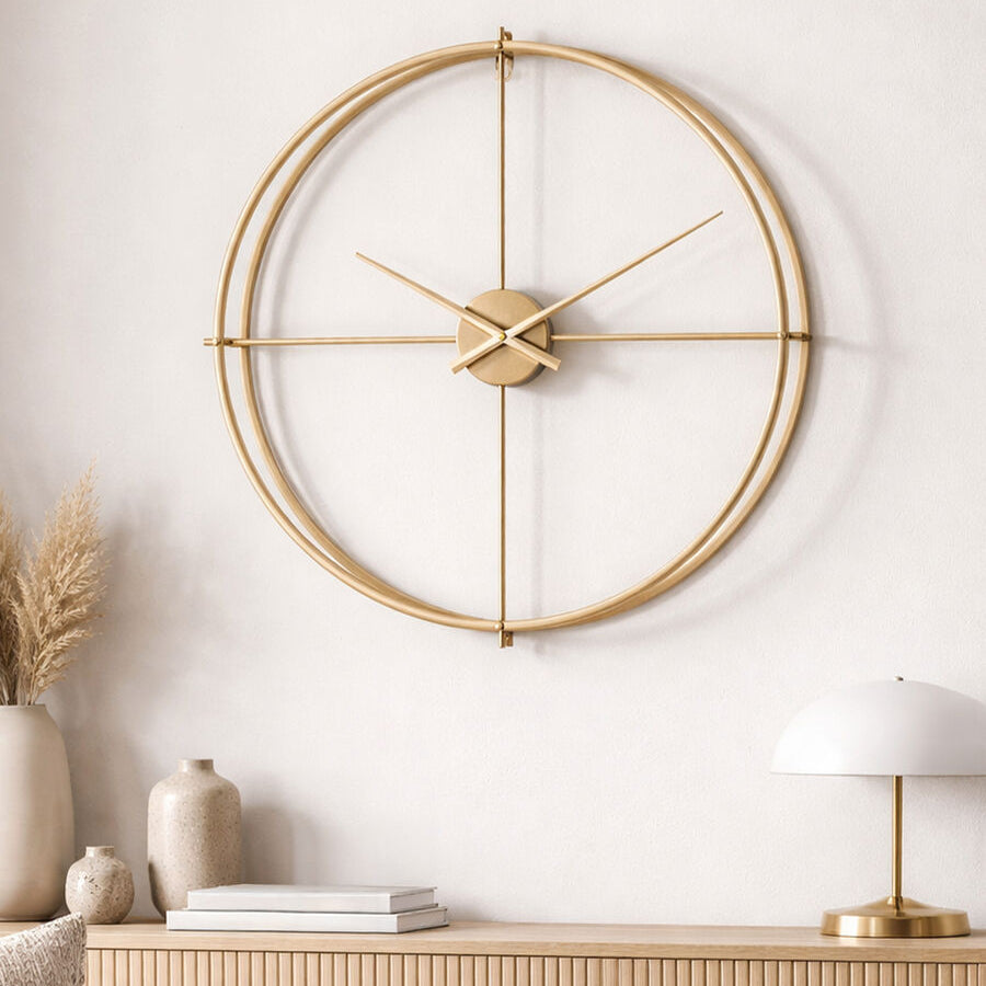 Gold wall clock on a white wall with a wooden cabinet and decorative items below.