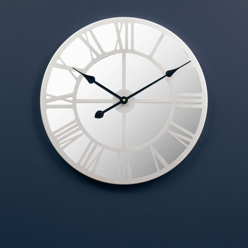 Silver wall clock with Roman numerals on a dark blue wall